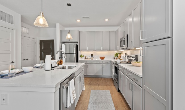 Modern apartment kitchen with gray cabinets, stainless steel appliances, and quartz countertops at Velo Circleport